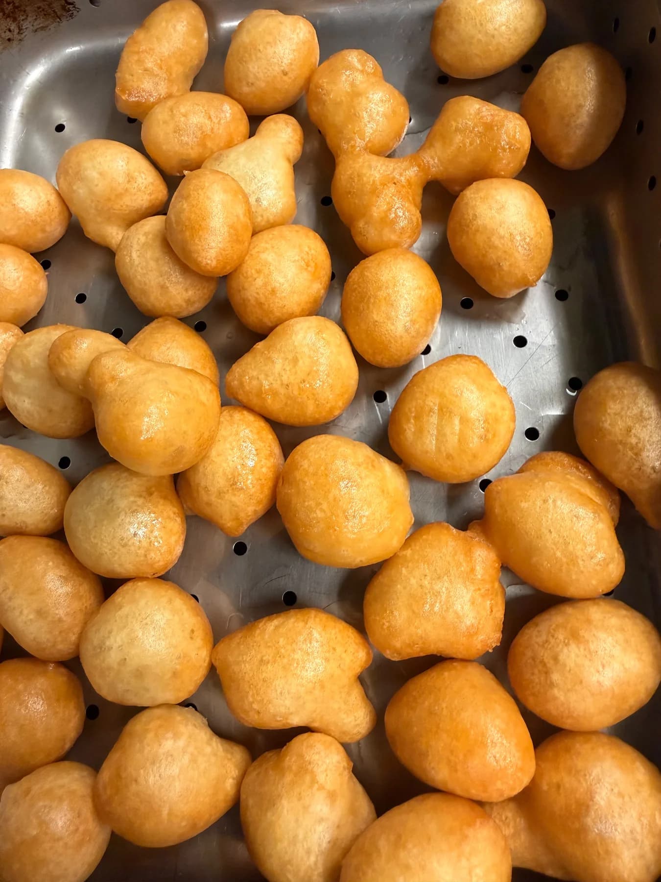 Freshly fried loukoumades resting in a kitchen tray at Zeus Greek